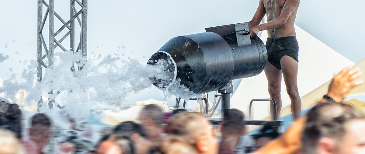 Dj using foam machine at foam party on the beach in music festival